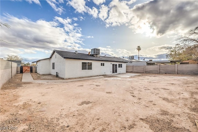 rear view of property with central air condition unit, stucco siding, a gate, a fenced backyard, and a patio area