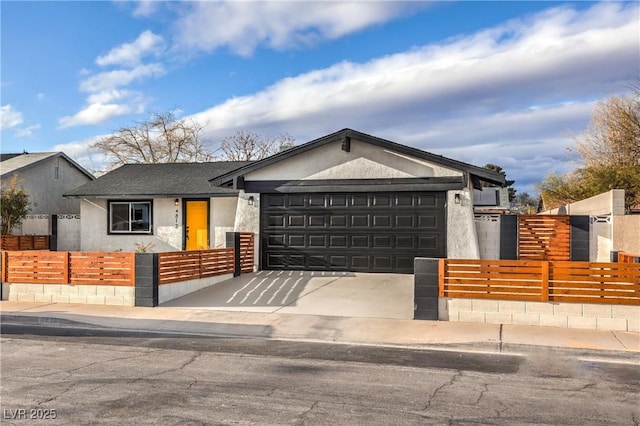 view of front facade with a fenced front yard, a garage, driveway, and stucco siding