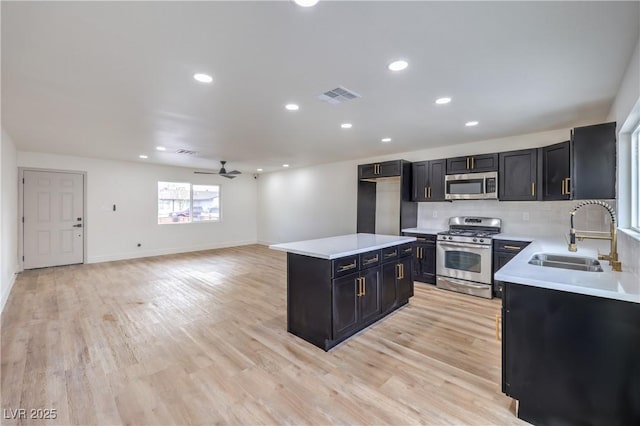 kitchen with visible vents, a sink, appliances with stainless steel finishes, light wood-style floors, and dark cabinets