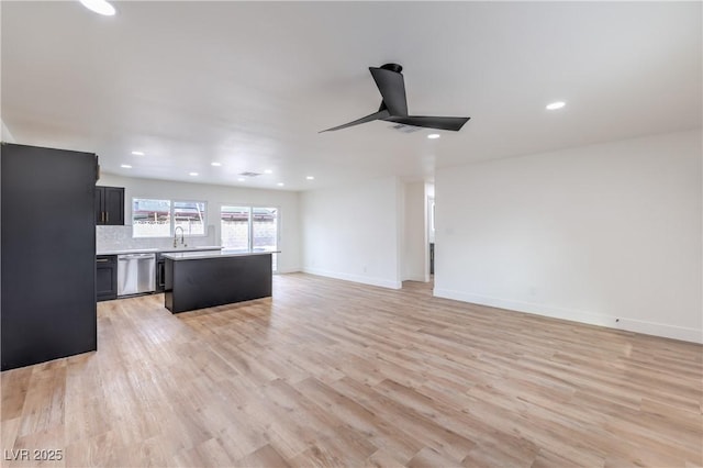 unfurnished living room featuring light wood finished floors, recessed lighting, baseboards, and a sink