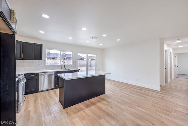 kitchen with visible vents, a kitchen island, light countertops, appliances with stainless steel finishes, and a sink