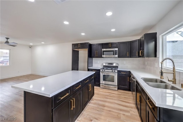 kitchen with light countertops, decorative backsplash, light wood-style floors, stainless steel appliances, and a sink