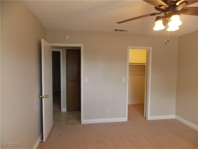 unfurnished bedroom with baseboards, visible vents, a spacious closet, a closet, and light carpet