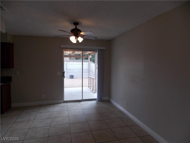 spare room featuring baseboards, a textured ceiling, ceiling fan, and light tile patterned flooring