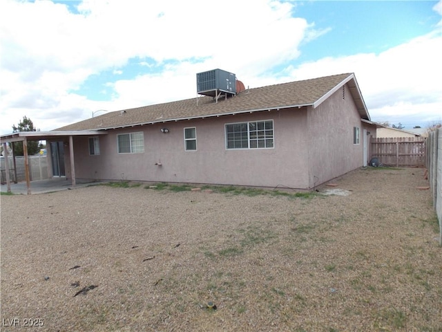 rear view of house with central air condition unit, stucco siding, a lawn, a patio, and a fenced backyard