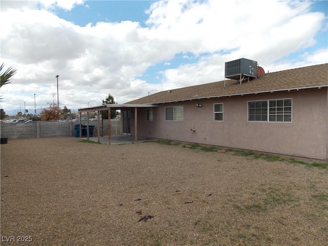 back of house featuring stucco siding, central AC unit, a fenced backyard, and a patio area