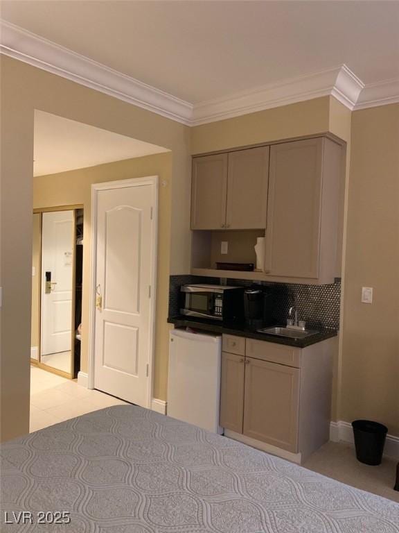 kitchen featuring a sink, backsplash, dark countertops, crown molding, and baseboards