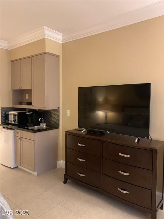 kitchen with white dishwasher, a sink, crown molding, dark countertops, and backsplash