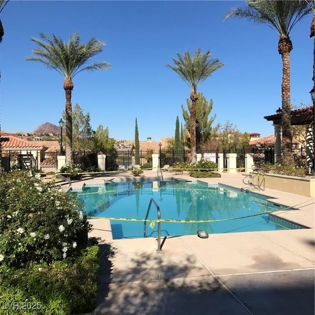 community pool with a patio and fence