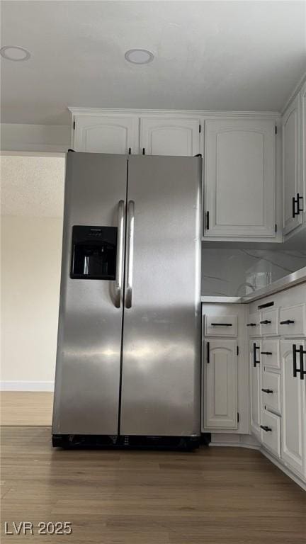 kitchen with wood finished floors, stainless steel refrigerator with ice dispenser, and white cabinetry