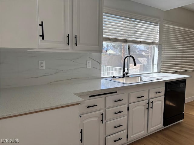 kitchen featuring light wood-style flooring, a sink, tasteful backsplash, white cabinetry, and dishwasher