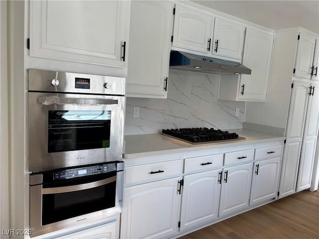 kitchen featuring under cabinet range hood, appliances with stainless steel finishes, white cabinetry, and light countertops