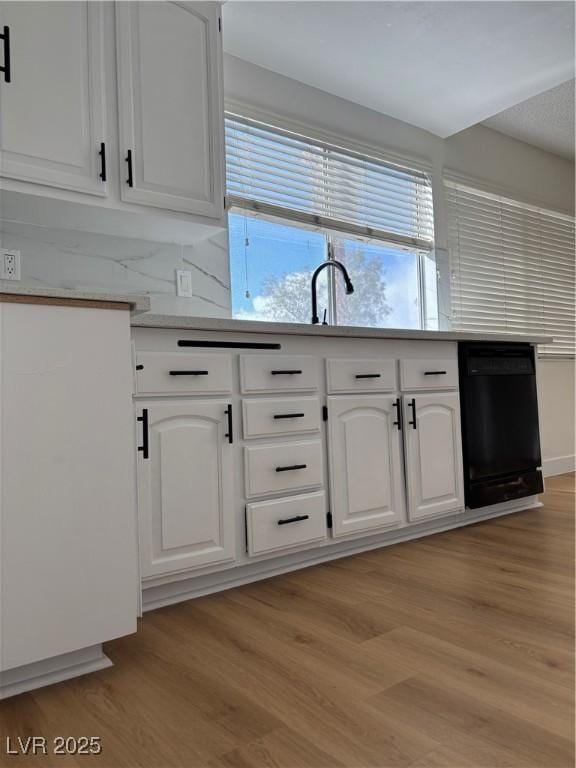 kitchen featuring black dishwasher, light wood-style flooring, light countertops, and white cabinetry