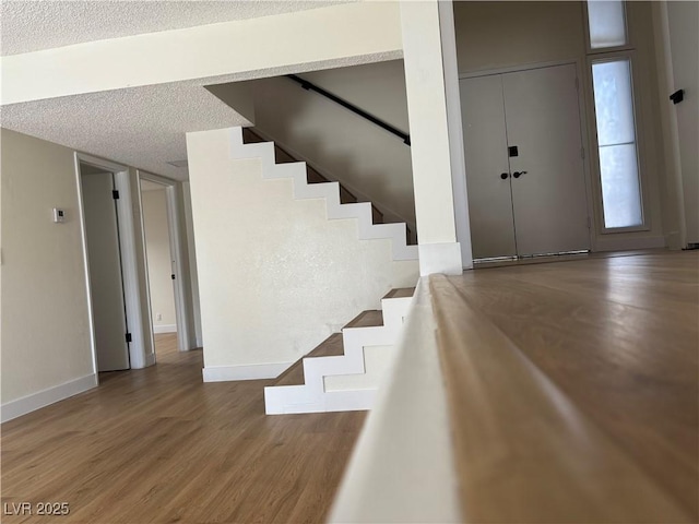 foyer with stairway, wood finished floors, baseboards, and a textured ceiling