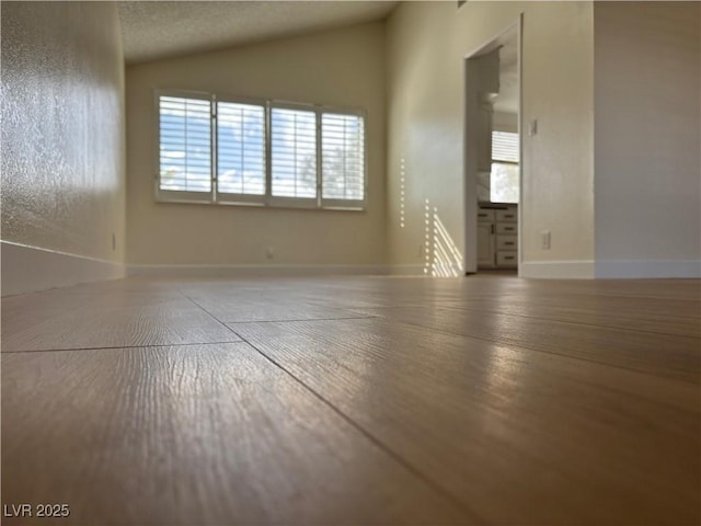 spare room with baseboards and vaulted ceiling