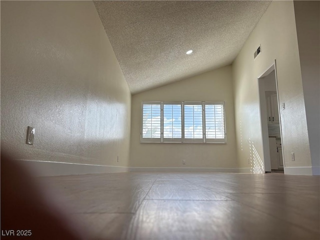 unfurnished room with lofted ceiling, a textured wall, visible vents, and a textured ceiling