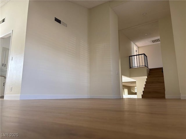 corridor with visible vents, baseboards, stairs, and a towering ceiling