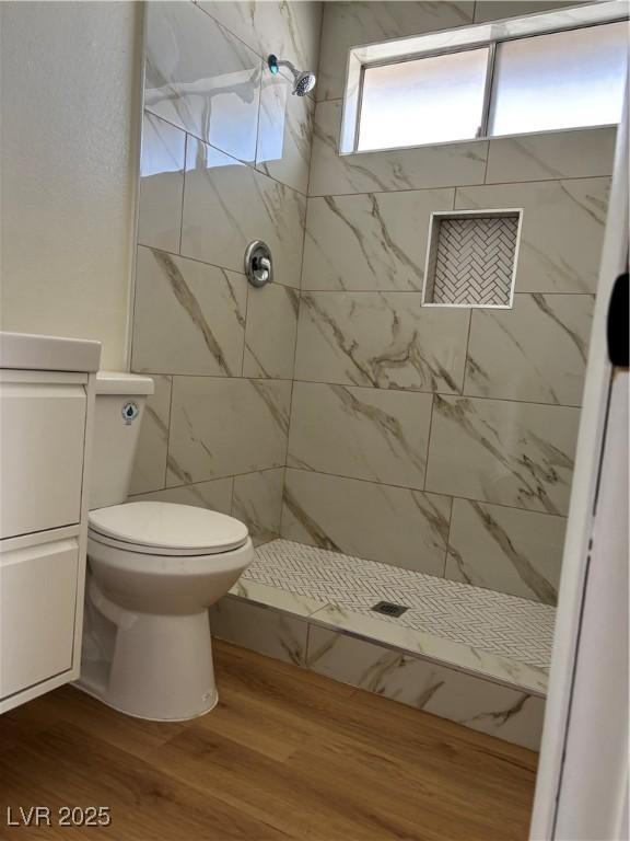 bathroom with a shower stall, toilet, and wood finished floors