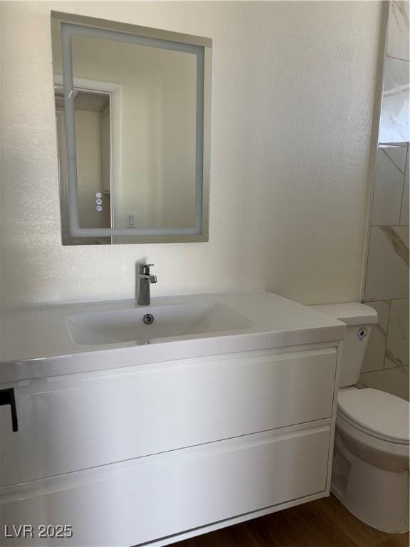 bathroom with vanity, toilet, and wood finished floors