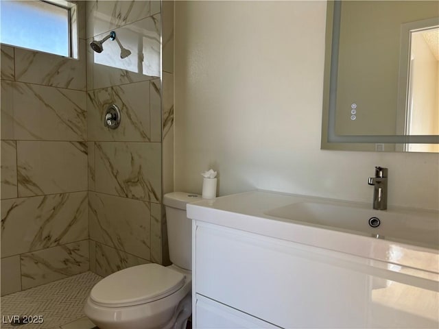 full bathroom featuring a tile shower, toilet, and vanity