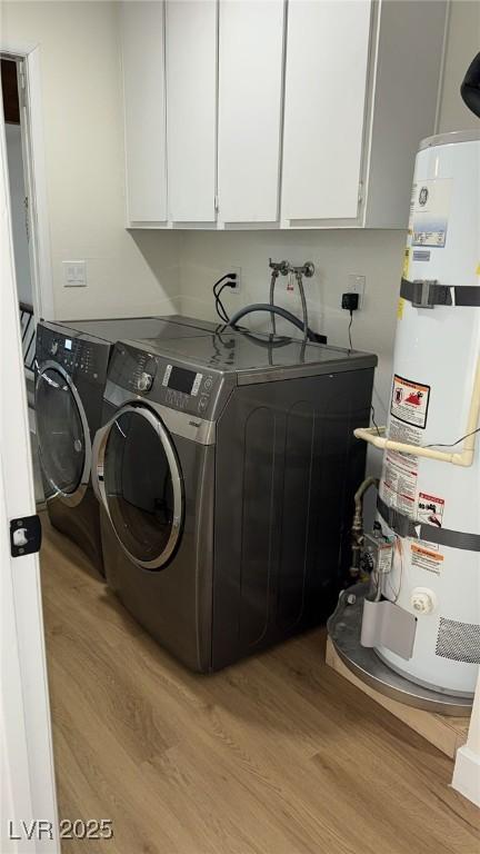 clothes washing area with cabinet space, light wood-style floors, secured water heater, and washing machine and dryer