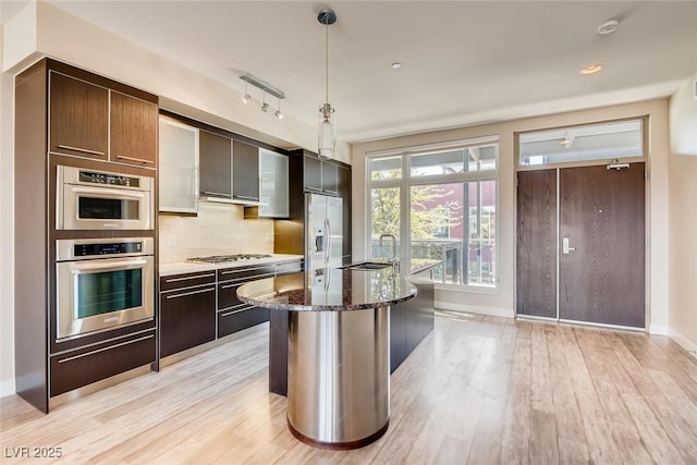 kitchen featuring a sink, appliances with stainless steel finishes, tasteful backsplash, and light wood-style flooring
