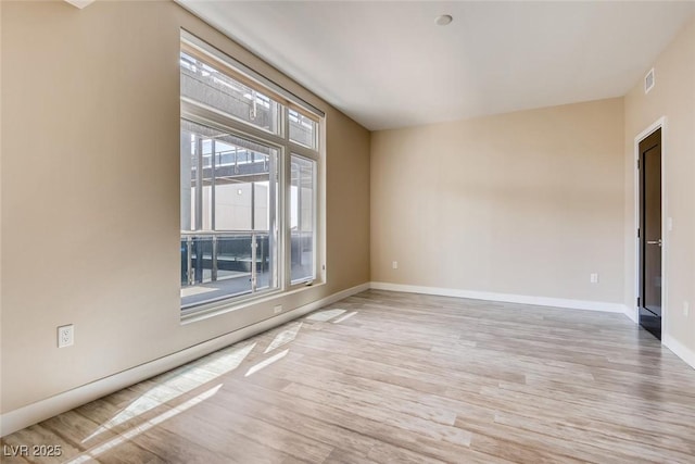 unfurnished room with baseboards, visible vents, and light wood-style flooring