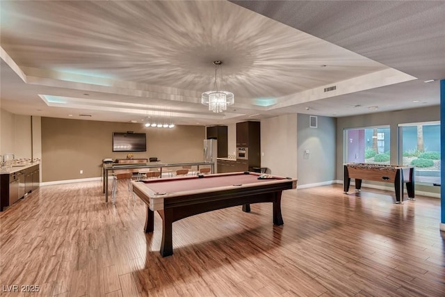 game room featuring pool table, a tray ceiling, baseboards, and light wood finished floors