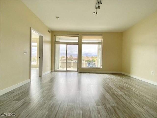 spare room with baseboards and wood finished floors