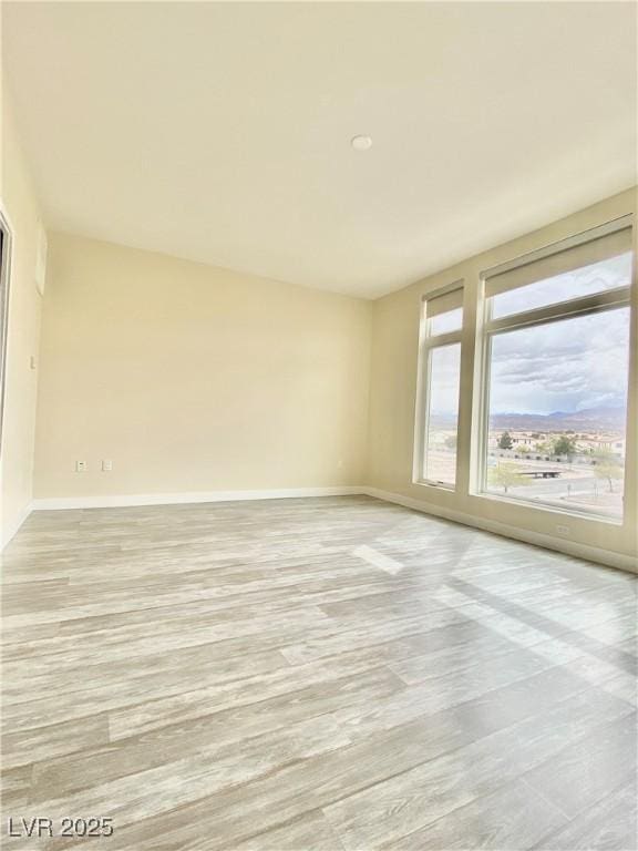 empty room featuring baseboards and light wood finished floors