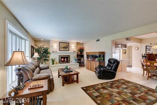 living area with light tile patterned floors, visible vents, and a warm lit fireplace