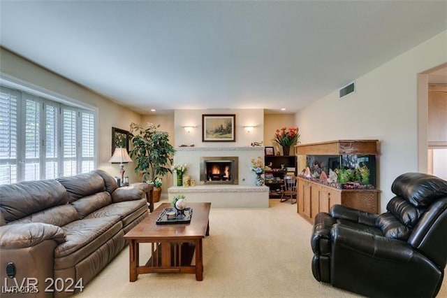 living room with recessed lighting, visible vents, a lit fireplace, and light colored carpet