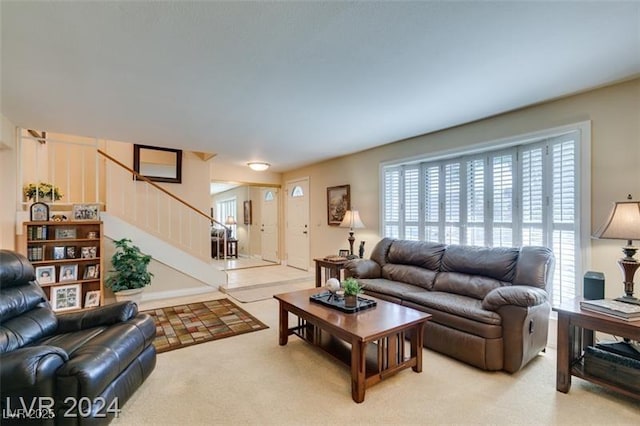 living area with light colored carpet and stairs