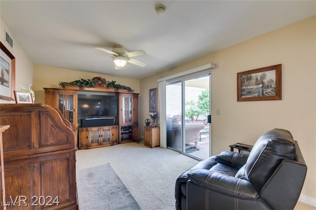 living room featuring a ceiling fan, visible vents, and light carpet