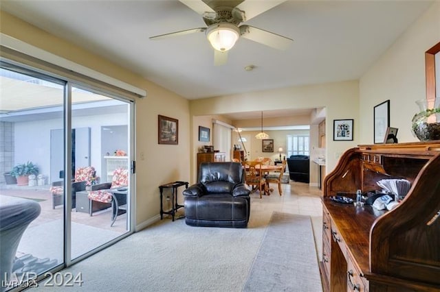 living room with a ceiling fan, light colored carpet, and baseboards