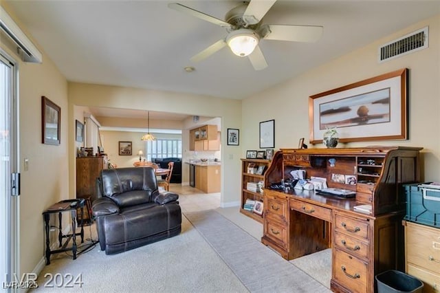 home office with visible vents, light colored carpet, baseboards, and a ceiling fan