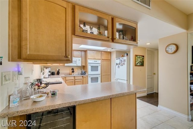 kitchen with white appliances, a peninsula, a sink, light countertops, and wine cooler