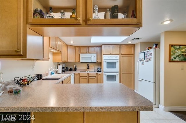 kitchen with white appliances, light brown cabinets, a peninsula, a sink, and light countertops