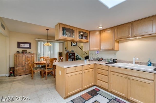 kitchen with a peninsula, glass insert cabinets, light brown cabinets, and a sink