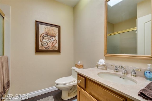 full bathroom with a shower with door, baseboards, toilet, wood finished floors, and vanity