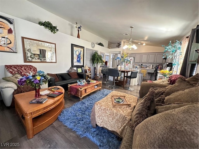 living room featuring wood finished floors, an inviting chandelier, and vaulted ceiling