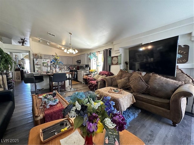 living room with an inviting chandelier, lofted ceiling, dark wood-style floors, and visible vents