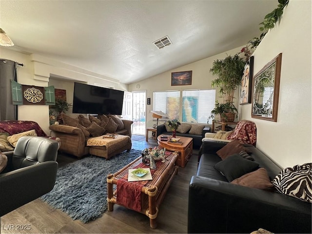 living area with vaulted ceiling, visible vents, and wood finished floors