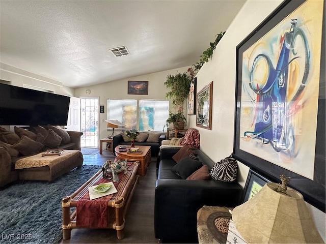 living area with visible vents, lofted ceiling, a textured ceiling, and wood finished floors