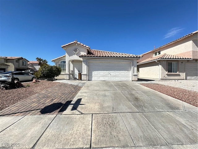 mediterranean / spanish house featuring stucco siding, a tiled roof, an attached garage, and driveway