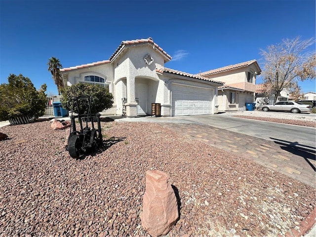 mediterranean / spanish house with a tile roof, an attached garage, driveway, and stucco siding