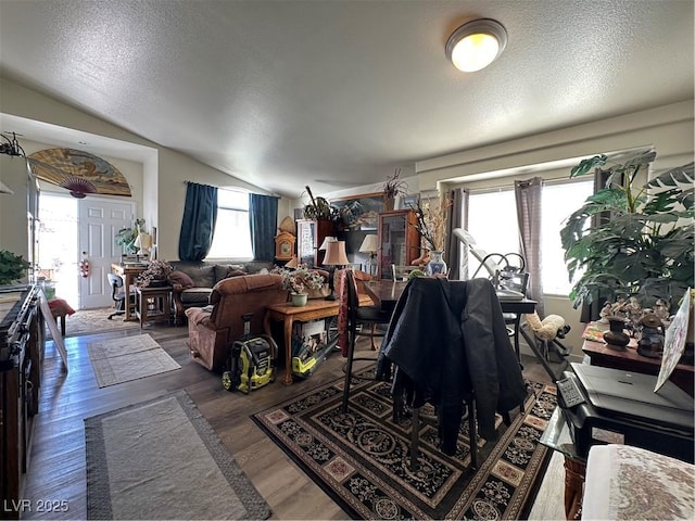 living area featuring a textured ceiling, wood finished floors, and vaulted ceiling