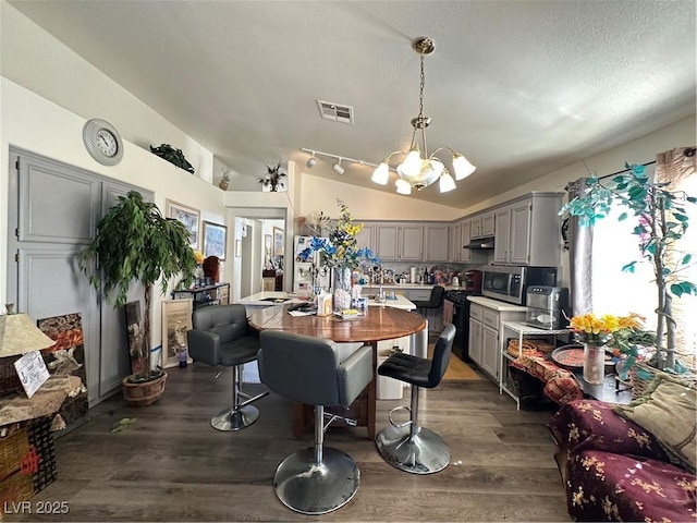 dining space with visible vents, dark wood-style flooring, vaulted ceiling, a textured ceiling, and a notable chandelier