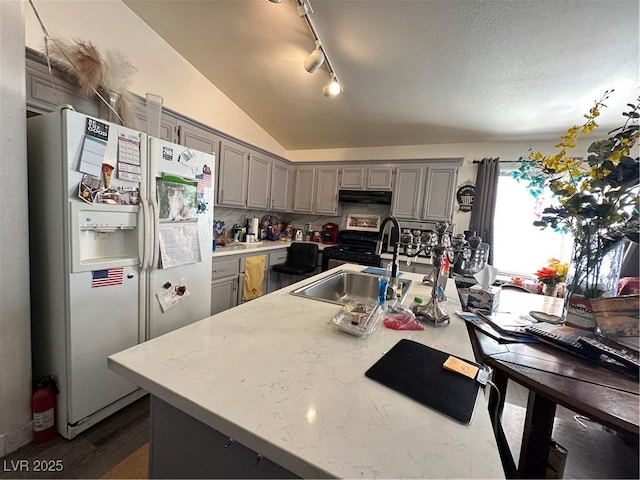 kitchen featuring under cabinet range hood, black range with gas stovetop, white fridge with ice dispenser, and gray cabinetry