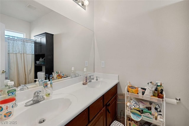 bathroom with double vanity, visible vents, toilet, and a sink